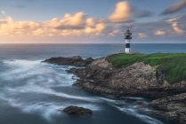 Paesaggio pittoresco di riva erbosa con faro situato vicino all'oceano blu a Faro Illa Pancha in Galizia in Spagna durante il giorno — Foto stock