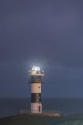 Malerische Landschaft mit grasbewachsenem Ufer und Leuchtturm in der Nähe des blauen Ozeans in Faro Illa Pancha in Galicien in Spanien bei Nacht — Stockfoto