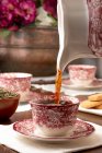 Tè caldo aromatico versato in tazza di ceramica posta sul tavolo per la colazione a casa — Foto stock
