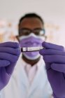 Afroamerikanischer Arzt im Medizinhandschuh demonstriert Reagenzglas mit Blutprobe auf weißem Hintergrund — Stockfoto