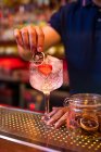 Неузнаваемый бармен, украшающий джин-тоник слайдом сухого лимона в баре — стоковое фото