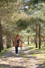 Corpo pieno di giovane donna a piedi e concentrato vicino alla vecchia bicicletta con cesto di vimini in legno nel parco — Foto stock