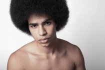 Young confident black man with six pack abs and Afro hairstyle looking at camera on white background — Stock Photo