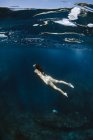 Touristin im Badeanzug schwimmt im sauberen, transparenten Meer während ihres Urlaubs im sonnigen tropischen Badeort — Stockfoto