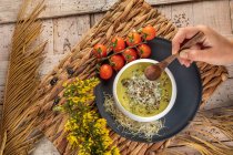Visão aérea da cultura chef anônimo com tigela de sopa de creme vegetariano gostoso com pistácios esmagados e condimentos em cima — Fotografia de Stock