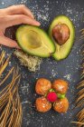 Dall'alto del raccolto anonimo cuoco con metà avocado maturo vicino crocchette fritte appetitose con lampone in cima — Foto stock