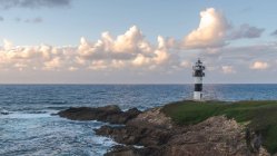 Cenário pitoresco da costa gramada com farol colocado perto do oceano azul em Faro Illa Pancha, na Galiza, em Espanha, durante o dia — Fotografia de Stock