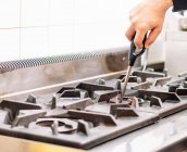 Crop anonymous chef burning gas stove with lighter before cooking in kitchen at restaurant — Stock Photo
