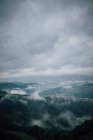 Picturesque view of majestic mounts with green woods under cloudy sky in misty weather — Stock Photo