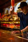 Junger asiatischer Barkeeper gießt Grapefruitsaft ins Glas, während er in der Bar einen Cocktail zubereitet — Stockfoto