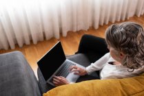 Visão superior do anônimo feminino distância trabalhador navegar internet no netbook no sofá em casa — Fotografia de Stock