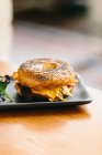 Antipasto panino al bagel con formaggio e pollo servito sul piatto con insalata di rucola sul tavolo nel caffè — Foto stock