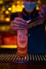 Руки неузнаваемого бармена, кладущего в чашку дробленый лёд во время приготовления коктейля в баре — стоковое фото