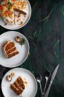Draufsicht auf leckeren Kuchen mit Frischkäse auf Tellern mit frischen Karottenscheiben und Walnüssen — Stockfoto