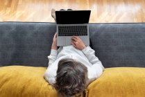 Visão superior do anônimo feminino distância trabalhador navegar internet no netbook no sofá em casa — Fotografia de Stock