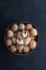 Кругла дерев'яна чаша, повна хрустких волоських горіхів з сухими нерівними горіхами на столі — стокове фото