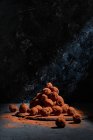 Tas de délicieuses truffes au chocolat en forme de boules empilées sur la table sur fond sombre en studio — Photo de stock