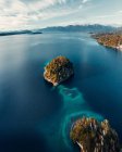 Сверху захватывающий вид с воздуха на остров в спокойном озере с бирюзовой водой, расположенной в высокогорье — стоковое фото