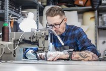 Чоловічий майстер використовує швейну машину при створенні оббивки для сидіння мотоцикла в майстерні — стокове фото
