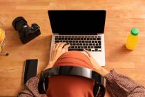 From above anonymous female in headscarf using modern netbook with black screen while sitting at desk — Stock Photo