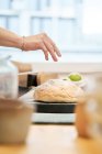 Cultiver anonyme femelle saupoudrer de pain de blé frais avec de la farine pendant le processus de cuisson dans la cuisine maison — Photo de stock