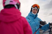 Pais concentrados em roupas esportivas quentes e capacete ensinando criança a esquiar ao lado de encostas nevadas na estação de esqui de inverno — Fotografia de Stock