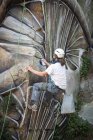 Vue de dos corps complet du peintre avec peinture en aérosol faisant graffiti accroché à la corde sur pente rocheuse raide — Photo de stock