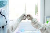 Anonymous doctors in uniforms greeting each other with high five at work in hospital — Stock Photo