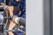 Чоловічий ремісник полірує шматок поролону з електричною шліфувальною машиною, роблячи сидіння для мотоцикла в майстерні — стокове фото