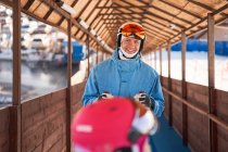 Cheerful father wearing ski helmet and warm sportswear standing in sunny outdoor sports club and looking at camera with smile — Stock Photo