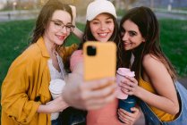Alegres melhores amigos do sexo feminino tomando auto-retrato no celular enquanto passam o tempo juntos na cidade — Fotografia de Stock