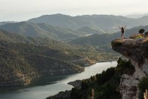 Fernsicht einer Wanderin, die mit ausgestreckten Armen am Hügelrand steht und beim Trekking in den Bergen im Sommer die Freiheit genießt — Stockfoto