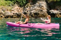 Side view travelers with paddles floating on turquoise seawater near the rocky shore on sunny day in Malaga Spain — Stock Photo