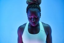 Junge afroamerikanische Sportlerin mit Afro-Zöpfen im Dutt und geschlossenen Augen auf blauem Hintergrund — Stockfoto