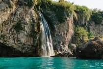 Amazing view of rapid cascade falling from rough cliff into turquoise rippling lagoon on sunny summer weather in Malaga Spain — Stock Photo