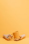 Mão de madeira ornamental criativa segurando caneca colorida no fundo amarelo no estúdio — Fotografia de Stock