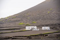 Modern white residential house located in middle of black lands against hills in haze — Photo de stock