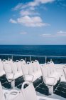 Leere weiße Stühle an Deck eines Kreuzfahrtschiffes, das im blauen Meerwasser segelt — Stockfoto