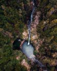 Espectacular vista del dron de la poderosa corriente de cascada que fluye en el lago en el bosque montañoso - foto de stock