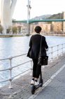 Зворотній перегляд невпізнаваного етнічного підприємця у формальному одязі, що їздить на електричному скутері на прогулянці в місті — стокове фото