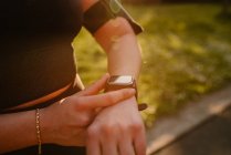 Schnuppern anonyme Sportlerin beobachtet Pulsfrequenz auf tragbarem Armband-Display während des Trainings in der Sonne — Stockfoto