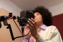 Chanteuse noire chantant une chanson contre microphone avec filtre pop tout en étant debout avec la main sur la hanche et impatiente en studio sonore — Photo de stock