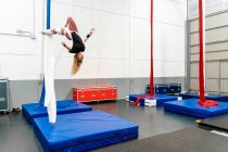 Volle Länge fit flexible Sportlerin in Aktivkleidung praktiziert Luftübungen auf Seide in modern ausgestatteten Sportverein — Stockfoto