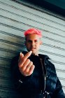 Trendy homosexueller Mann in gepolsterter Jacke mit rosa Haaren zeigt Nagel, während er in die Kamera schaut — Stockfoto