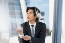 Joven ejecutivo masculino étnico bien vestido en camisa blanca con corbata y chaqueta sobre fondo borroso - foto de stock