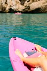 Vue latérale du voyageur anonyme avec pagaies flottant sur l'eau de mer turquoise près de la rive rocheuse par une journée ensoleillée à Malaga en Espagne — Photo de stock