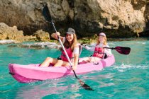 Viaggiatori vista laterale con pagaie galleggianti su acqua di mare turchese vicino alla riva rocciosa nella giornata di sole a Malaga Spagna — Foto stock