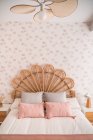 Comodo letto di testiera in rattan vintage naturale carino con cuscini ornamentali in una stanza — Foto stock