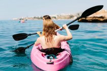 Back view travelers with paddles floating on turquoise seawater near the rocky shore on sunny day in Malaga Spain — Stock Photo