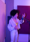 Чорна співачка виконує пісню проти мікрофона з поп-фільтром, стоячи з рукою на стегні і закритими очима в звуковій студії — стокове фото